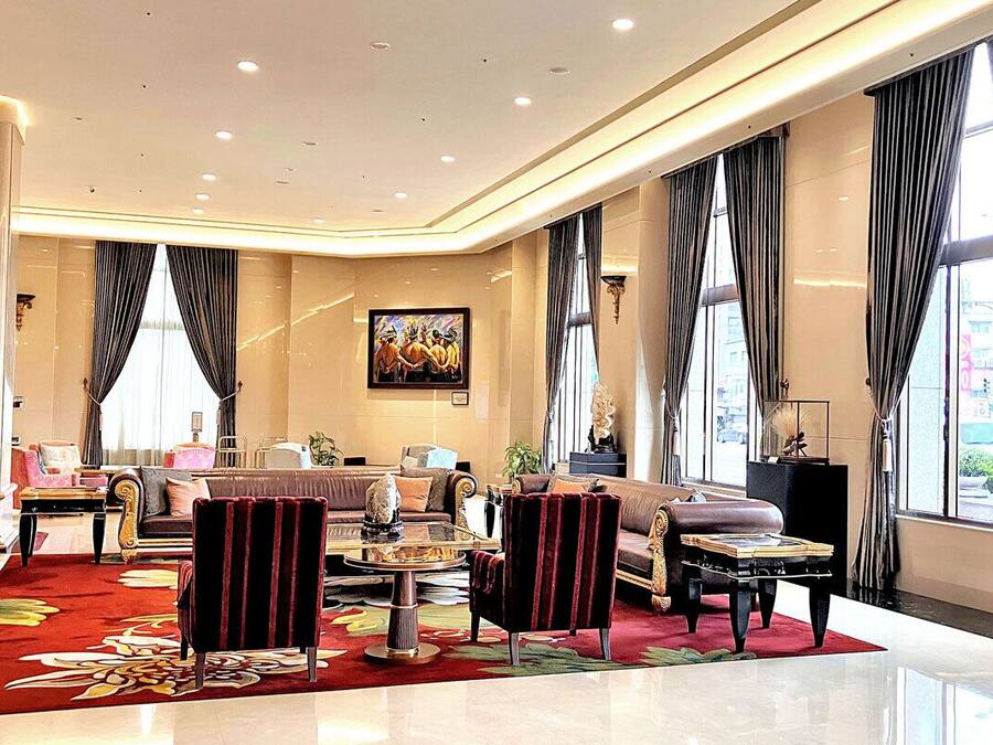 A spacious lobby with a red carpet, plush seating, and large windows offering a city view.