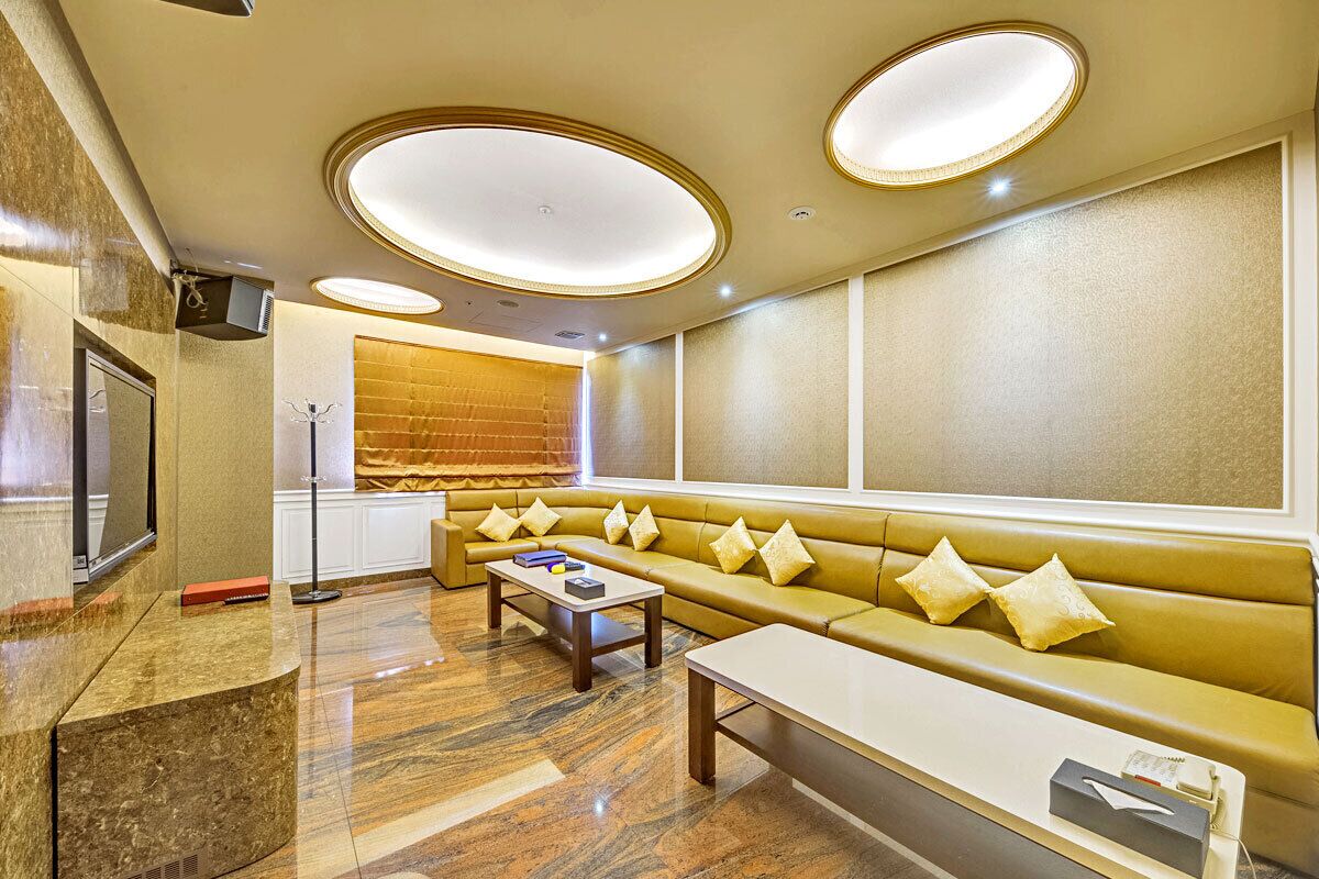 A modern hotel lobby with a seating area, a reception desk, and a large window.