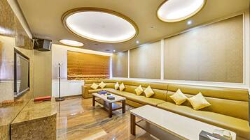 A modern hotel lobby with a seating area, a reception desk, and a large window.