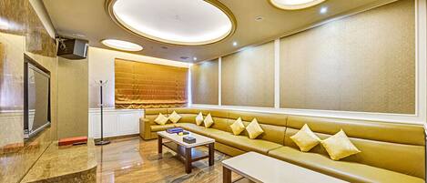 A modern hotel lobby with a seating area, a reception desk, and a large window.