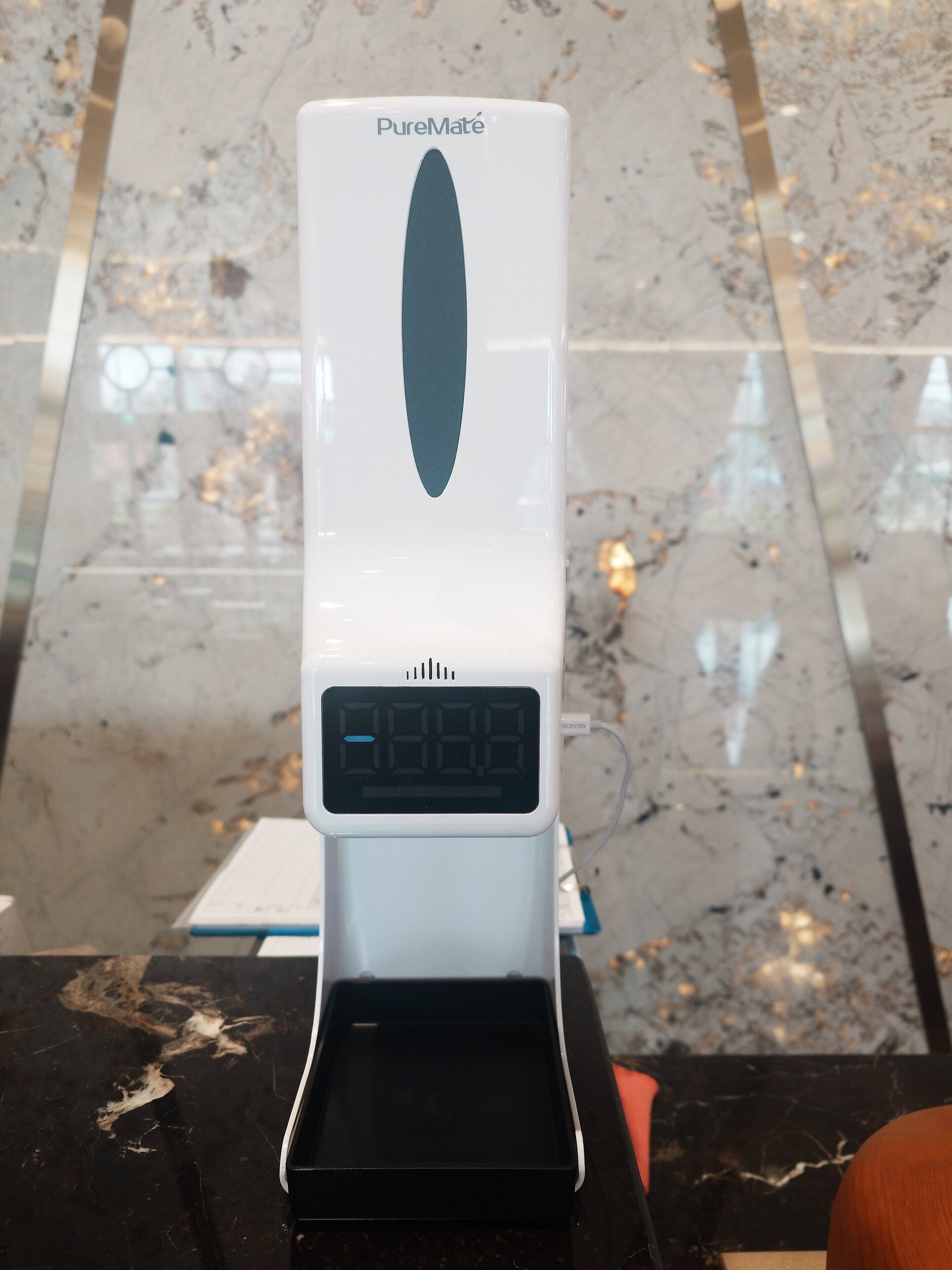 Eine PureMate Kaffeemaschine mit digitaler Anzeige steht auf einer Marmorarbeitsplatte.