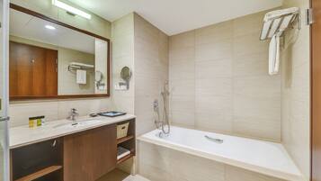 A modern bathroom with a large mirror, a bathtub, a sink, and a towel rack.