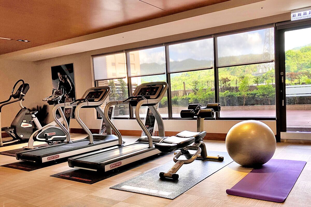 A gym with treadmills, elliptical machines, and an exercise ball.