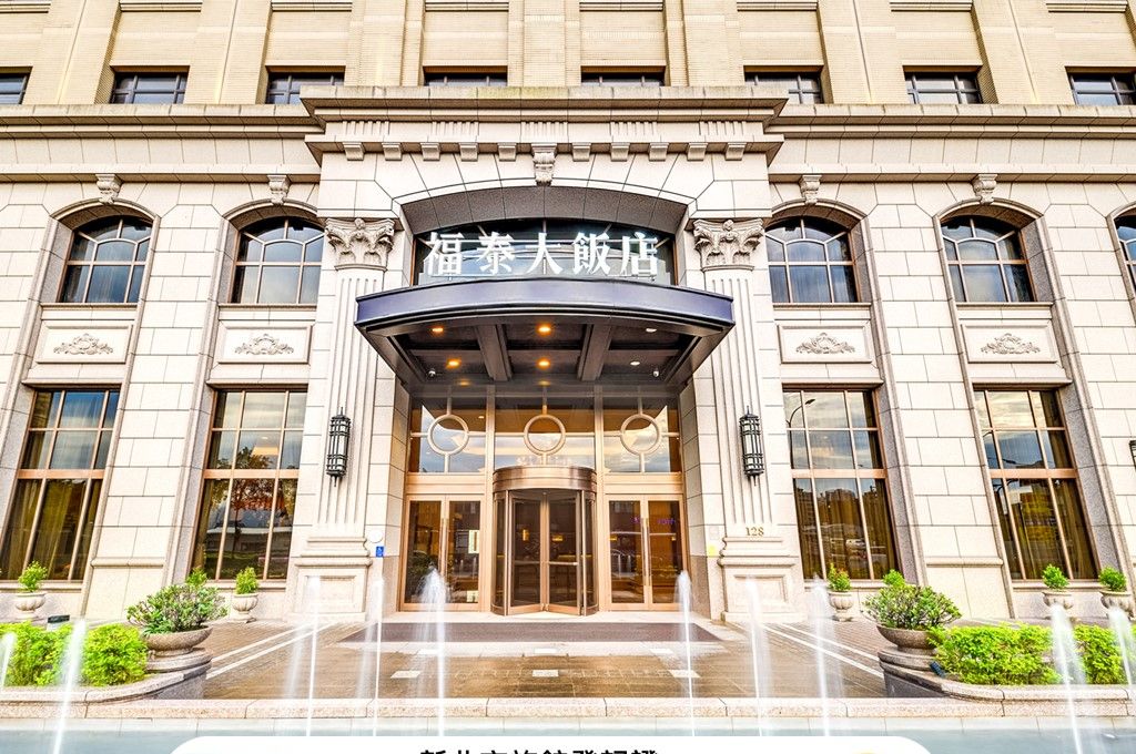 A hotel entrance with a classic facade, large windows, and a central entrance with a canopy.