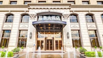 A hotel entrance with a classic facade, large windows, and a central entrance with a canopy.