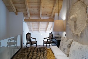 A modern living room with wooden beams, two upholstered chairs, a sofa, a large lamp, and a wall-mounted sculpture. - Casa Alana (Polientes)