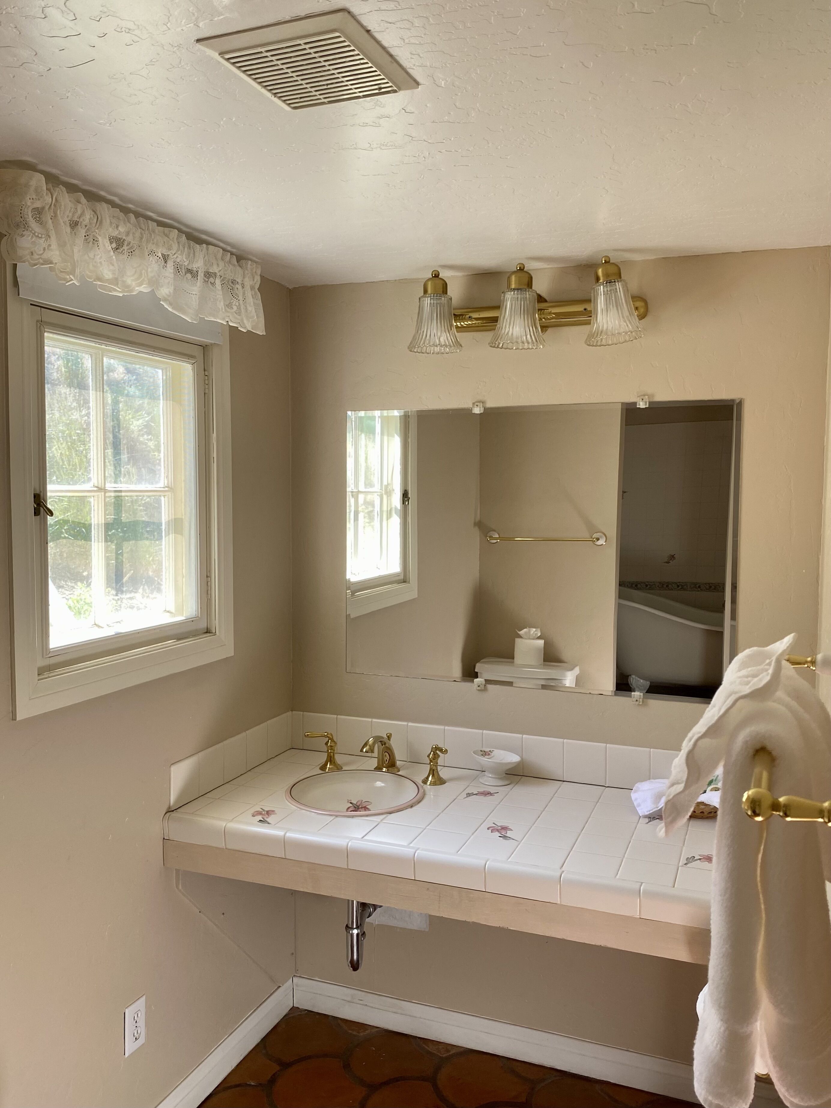 A bathroom with a double sink, a mirror, a window, and a towel rack.