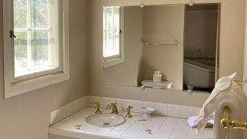 A bathroom with a double sink, a mirror, a window, and a towel rack.