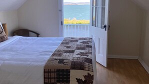 A bedroom with a bed, a chair, a door leading to a balcony with a view of the sea. - Tioga Lodge At Mono Lake (Lee Vining)