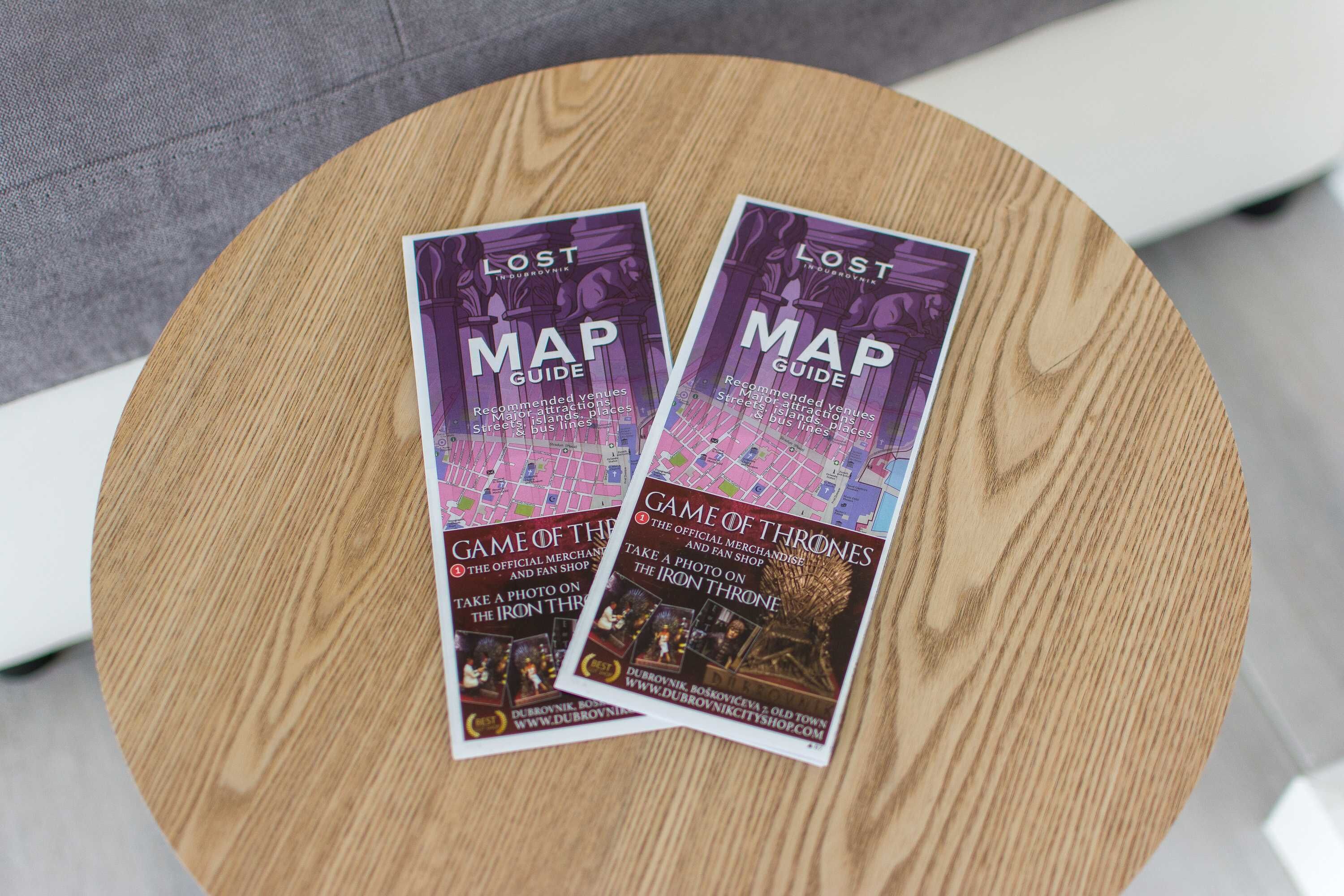 Deux brochures intitulées « Lost Map Guide » sont posées sur une table ronde en bois.