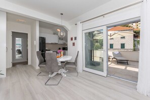 A modern apartment with a dining area, kitchen, and a balcony with a view. - Apartment Gloria (Dubrovnik)