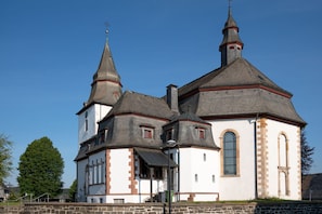 Une église à la façade blanche, dotée de deux tours et d’une horloge.