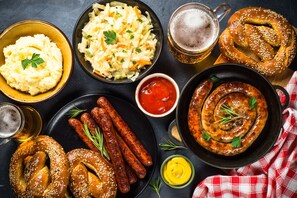 A variety of food items including sausages, a pretzel, mashed potatoes, and sauerkraut, along with beer and ketchup.