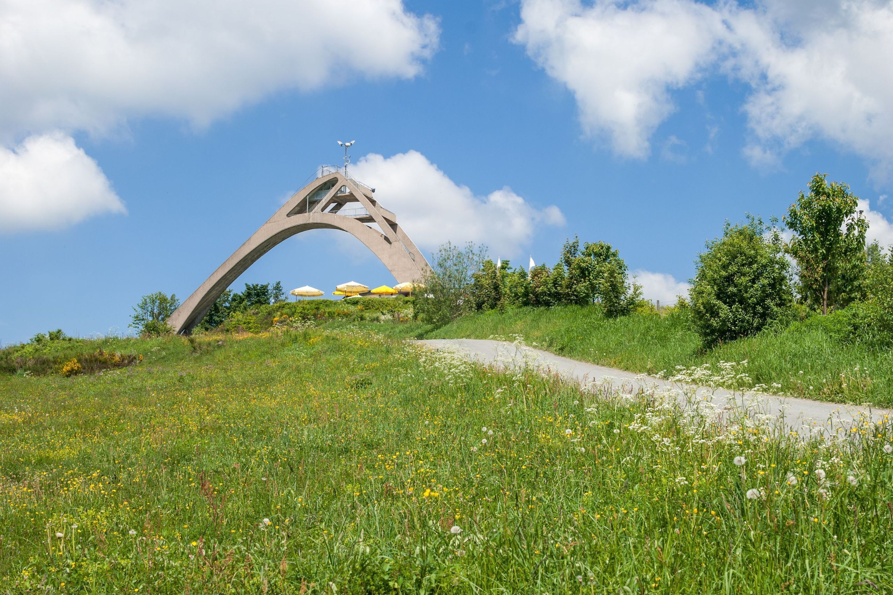 A concrete arch structure in a grassy field with a clear sky.