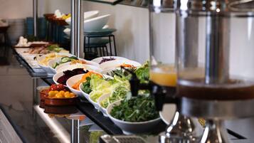 A buffet with various dishes including salads, fruits, and vegetables.