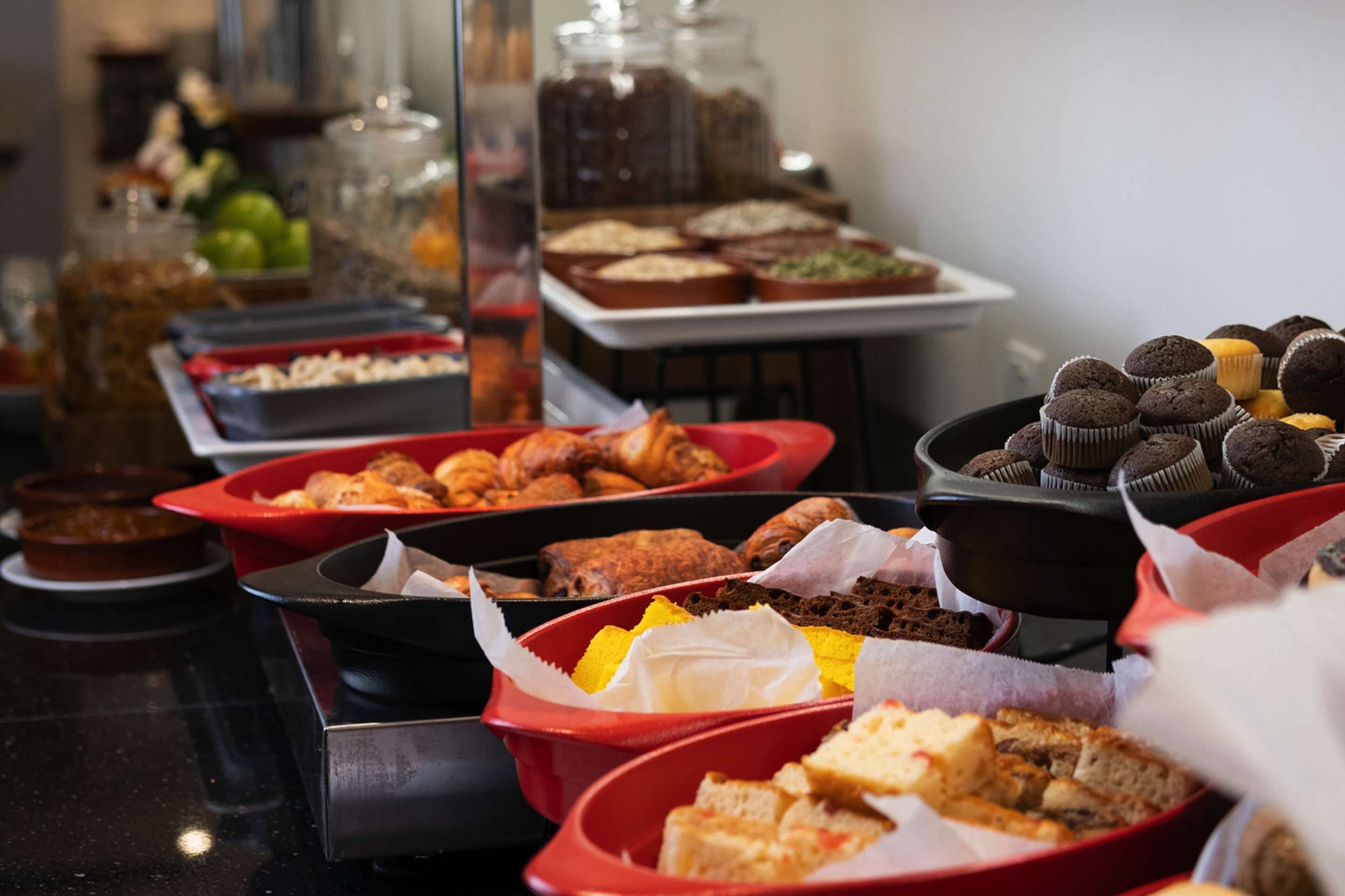 A buffet with various food items including pastries, cakes, and sandwiches.