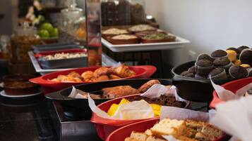 A buffet with various food items including pastries, cakes, and sandwiches.