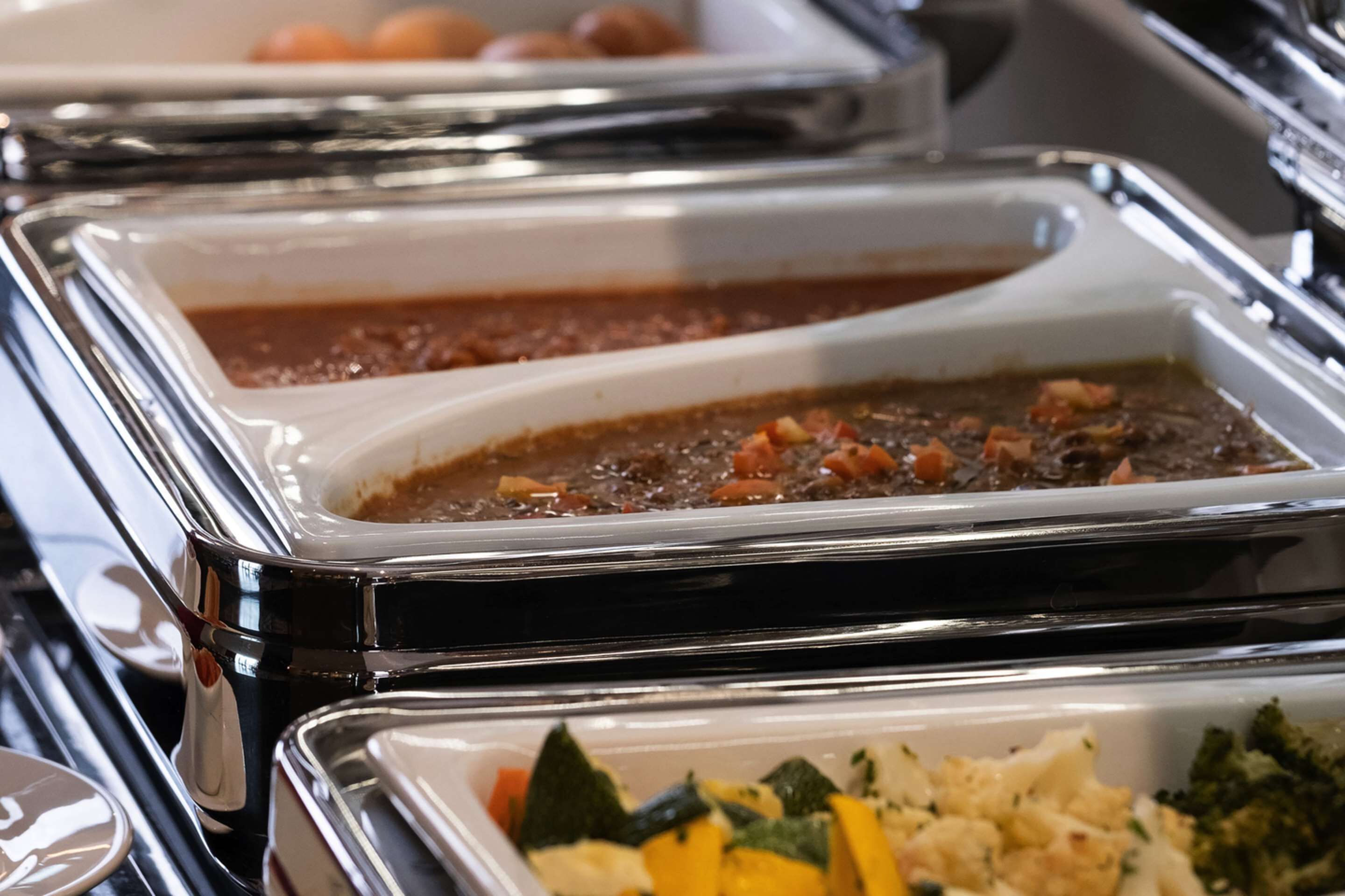 Ein Buffet mit verschiedenen Speisen, darunter ein Braten, eine cremige Auflauffspeise und ein Gemüsegericht.