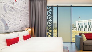 A hotel room with a large bed, a sofa, a map on the wall, and a view of the city through the window. - IntercityHotel Muscat (Muscat)
