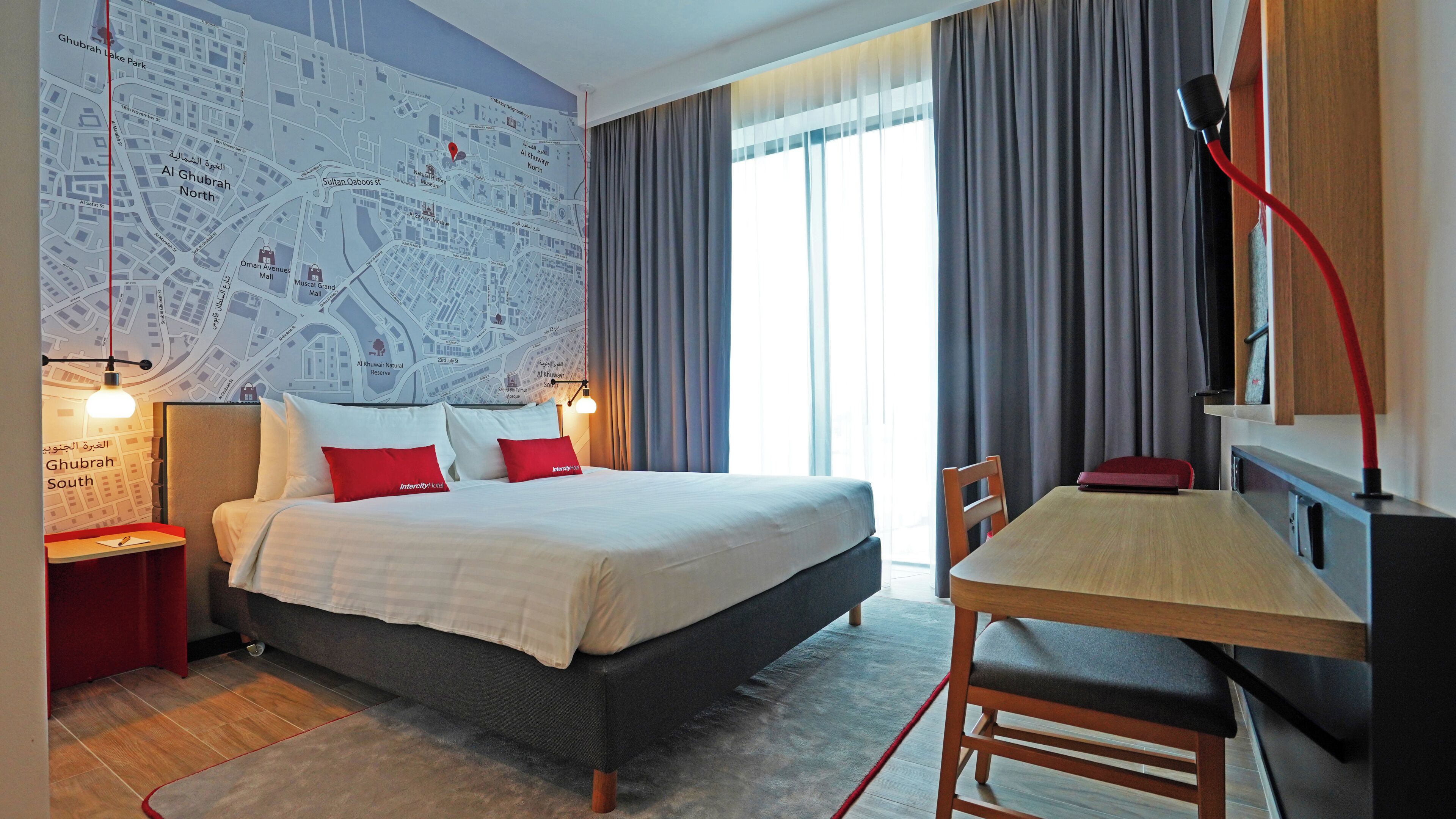 Een hotelkamer met een groot bed, een bureau en een kaart aan de muur.
