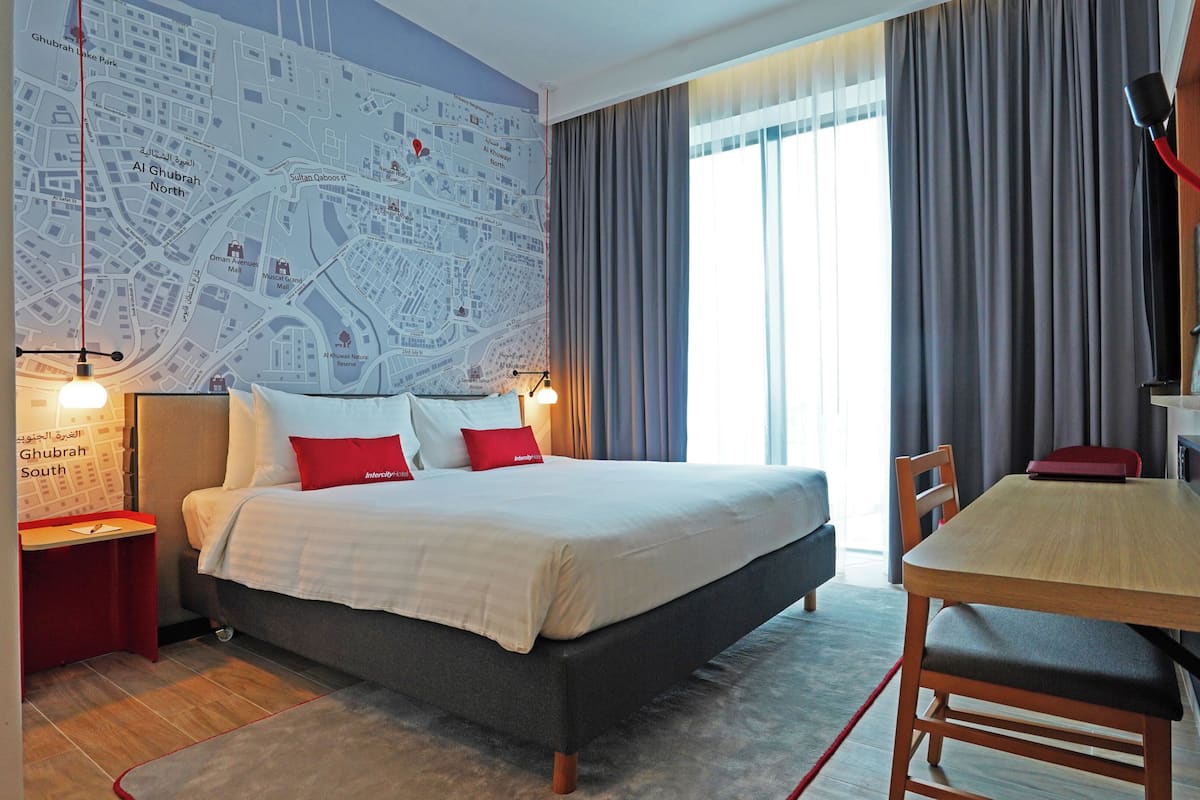 Ein Hotelzimmer mit einem großen Bett, einem Schreibtisch und einer Karte an der Wand.