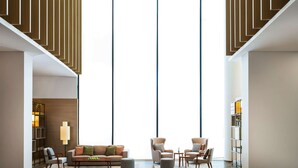 A spacious living area with a modern sofa set, armchairs, and a coffee table. There are bookshelves and a floor lamp. - IntercityHotel Muscat (Muscat)