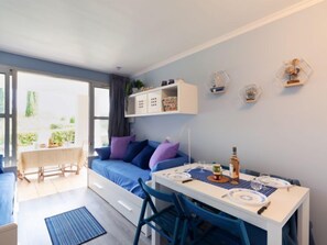 Un espacio habitable compacto con un sofá, una mesa de comedor y una pequeña cocina.
