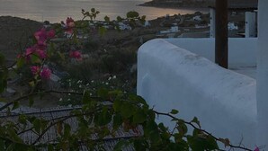 A coastal view with a sunset, a white building, and pink flowers in the foreground. - Breathtaking views (Plintri)