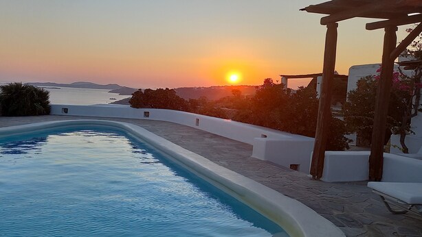A swimming pool with a view of the sunset over the sea, surrounded by white walls and wooden pergolas. - Breathtaking views (Plintri)