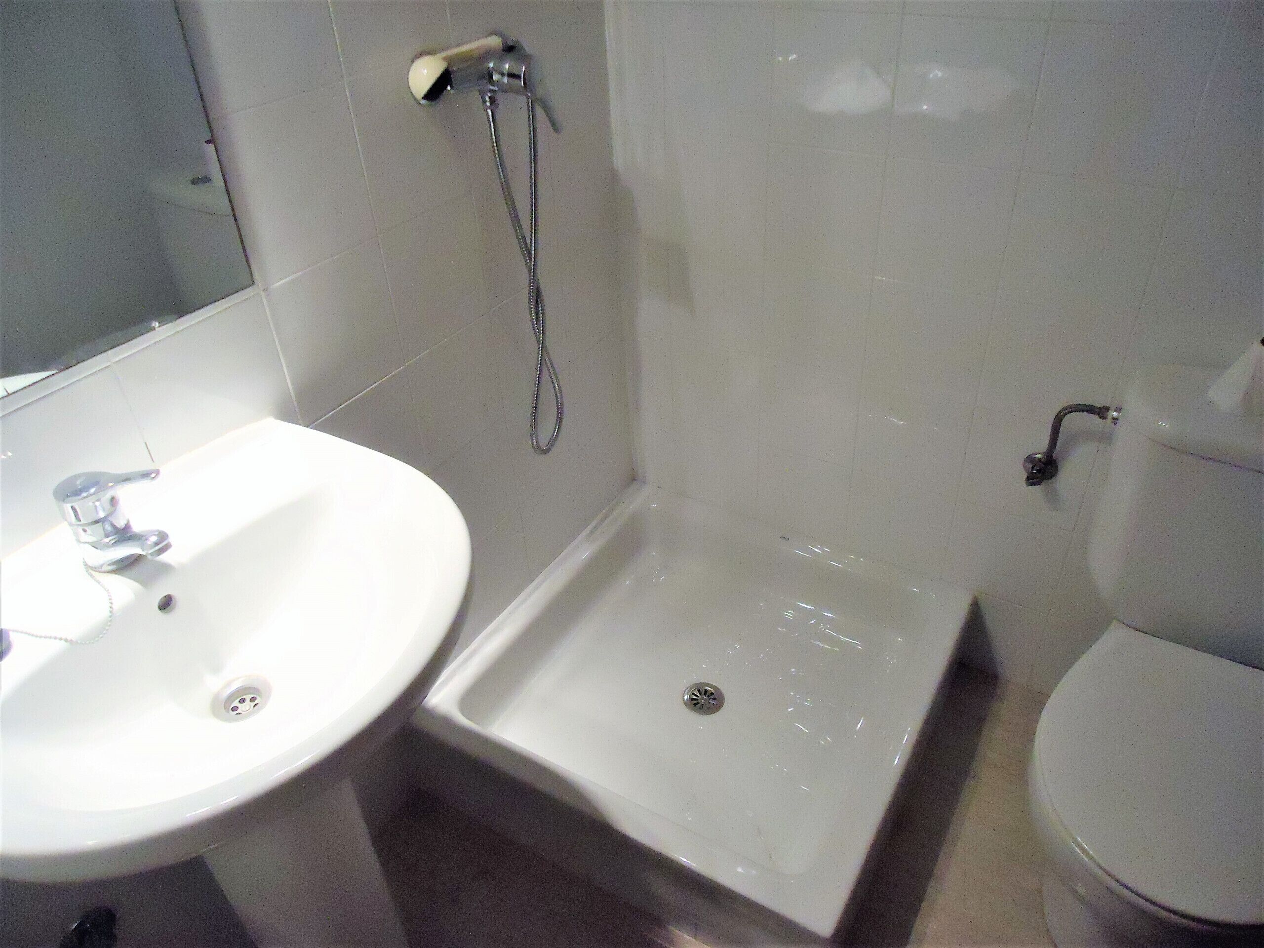A bathroom with a white sink, a shower, and a toilet.