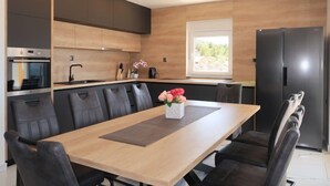 A modern kitchen with a central island, black chairs, and a wooden dining table.