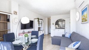 Un salon moderne comprenant un coin repas, une cuisine et un téléviseur fixé au mur.