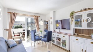Un salon moderne comprenant un canapé, une table à manger, des chaises et un téléviseur.