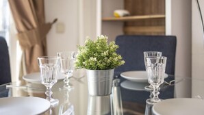 Une table à manger sur laquelle se trouve un seau en métal contenant une petite plante, entourée de verres à vin et d’assiettes vides.