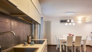Eine moderne Küche mit Einbauherd, Spüle und Essbereich mit weißen Stühlen und einem Tisch.
