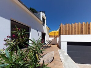 A modern house with a garage, a wooden fence, and a yellow umbrella.