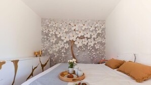A bedroom with a bed, a bedside table, a decorative wall, and a tray with fruits and a vase. - Le Rahic by Interhome (Carnac)