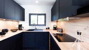 A modern kitchen with dark cabinets, a wooden countertop, a sink, and a window providing natural light. - Le Rahic by Interhome (Carnac)