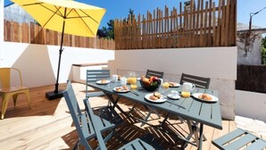 An outdoor dining area with a table set for breakfast, including plates, glasses, and a fruit bowl. - Le Rahic by Interhome (Carnac)