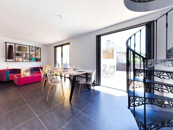 A modern living room with a dining area, a staircase, and a view of the outdoors. - Le Rahic by Interhome (Carnac)
