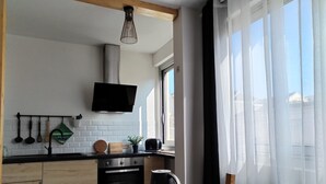 Une cuisine moderne avec une table en bois, des appareils électroménagers noirs et un téléviseur fixé au mur.