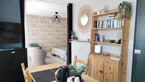 Un salon moderne avec un mur en briques, une table basse en bois sur laquelle se trouvent une bouilloire et des tasses, une bibliothèque et un grand miroir.