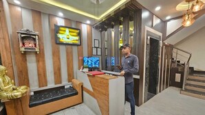 Una zona de recepción con un mostrador de madera, una estatua de Buda y una pantalla de televisión.