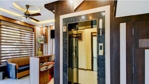 Un interior moderno con un sofá, un ventilador de techo y una puerta de ascensor de vidrio.