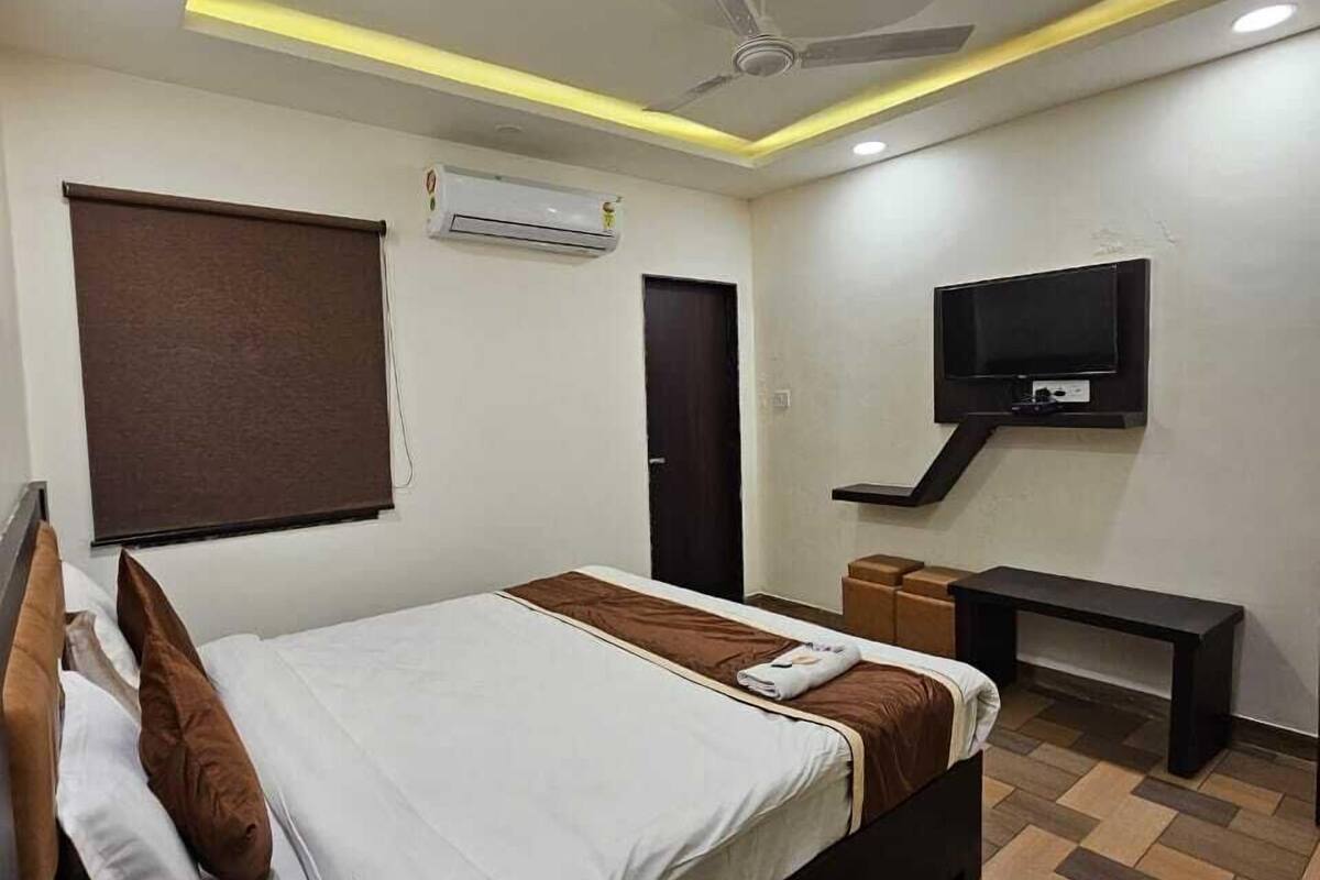 Ein modernes Hotelzimmer mit Bett, Schreibtisch, Fernseher und Deckenventilator.