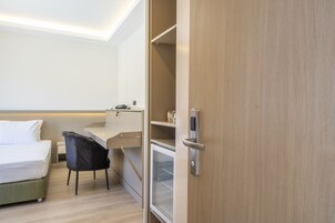 Una habitación de hotel con cama, escritorio, silla y minibar.