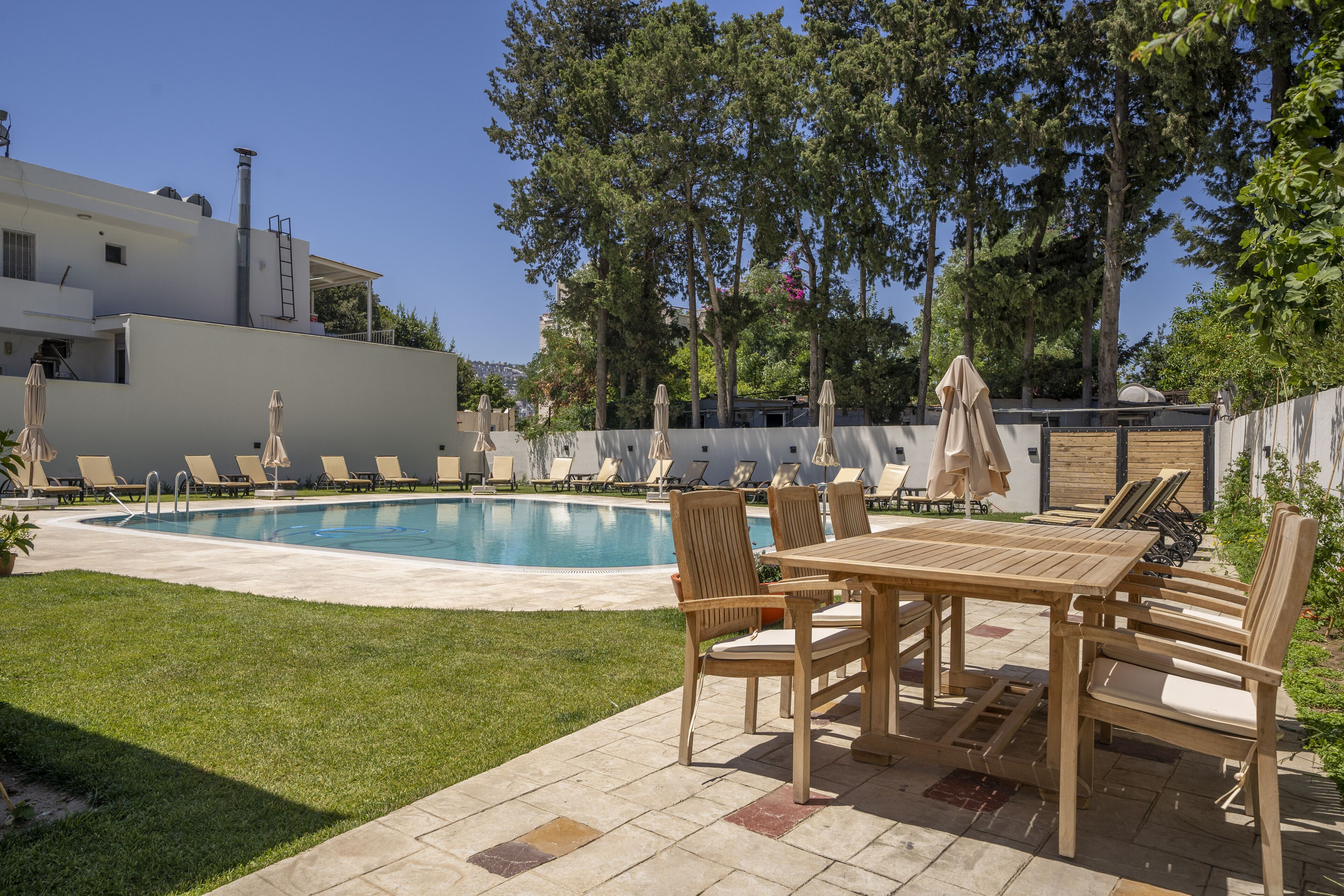 A pool area with lounge chairs and a wooden table.