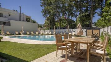 A pool area with lounge chairs and a wooden table.