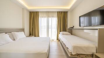 A hotel room with two beds, a flat-screen TV, and a window with curtains.