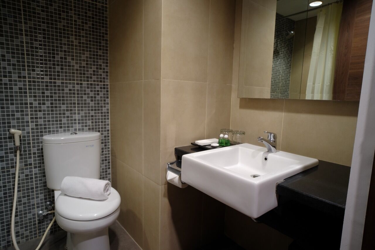 A bathroom with a toilet, sink, and mirror.